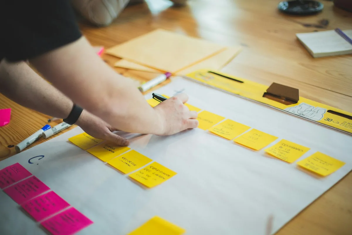 Hands arranging sticky notes on a sheet of paper