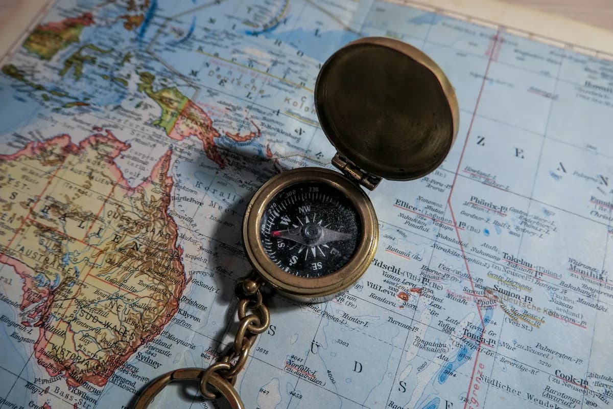A brass compass lying on an open map